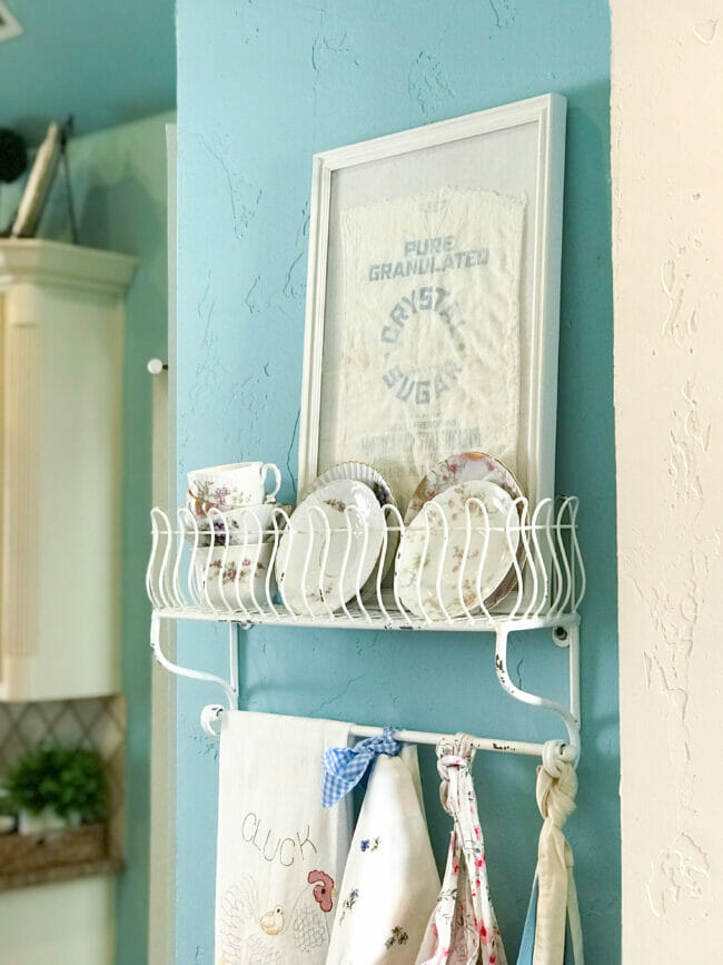 metal rack with aprons, teacups and framed sugar shack