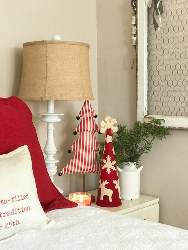 Christmas bedside table with ted and white striped trees and greenery with lamp