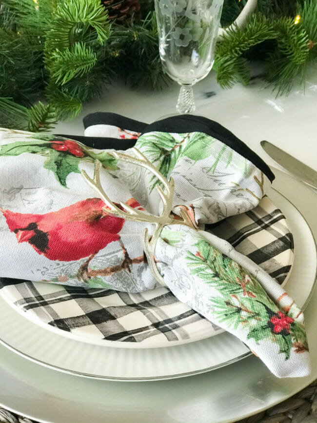 black plaid place setting with Christmas napkins and antler napkin ring