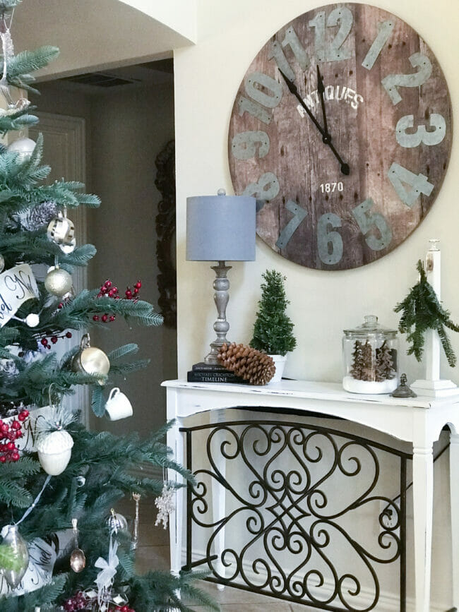 part of a Christmas tree with a table, lamp and large clock and Christmas decor