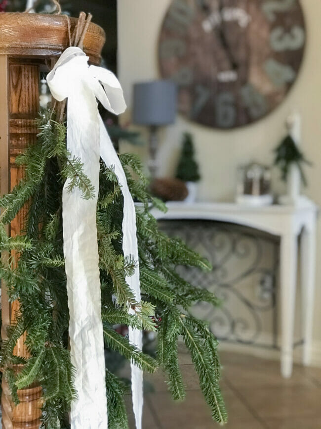 green bough with white bow hanging on stairway railing