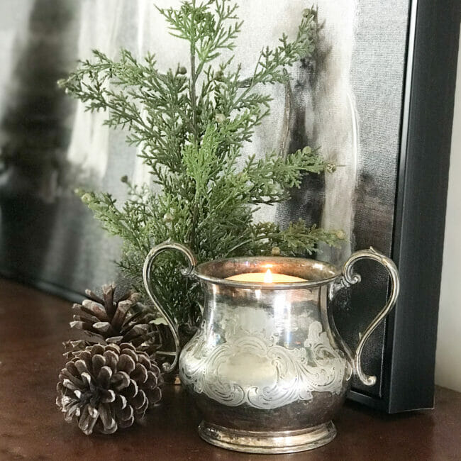 small pine tree with pinecones and a candle inside a silver creamer