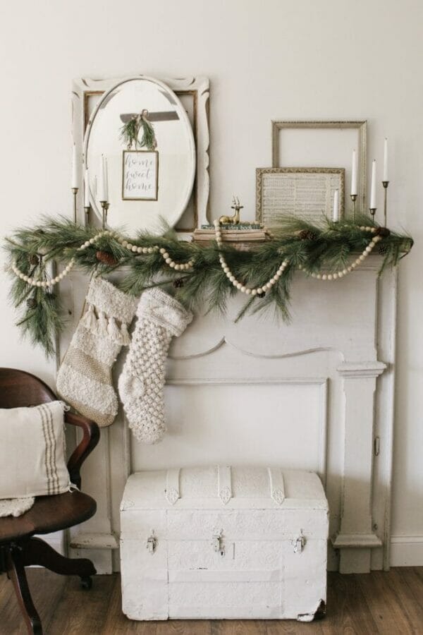 white mantel with frames, mirrors, greens and beads