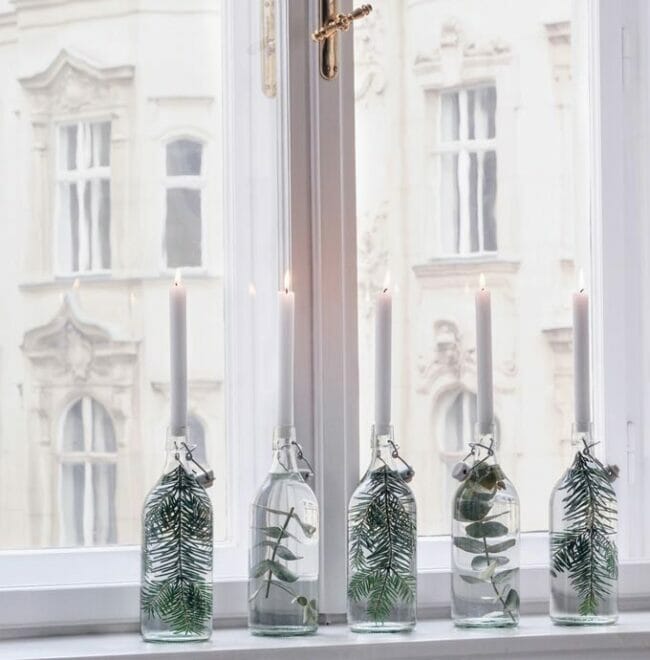 window with clear bottles, plants inside with white candles