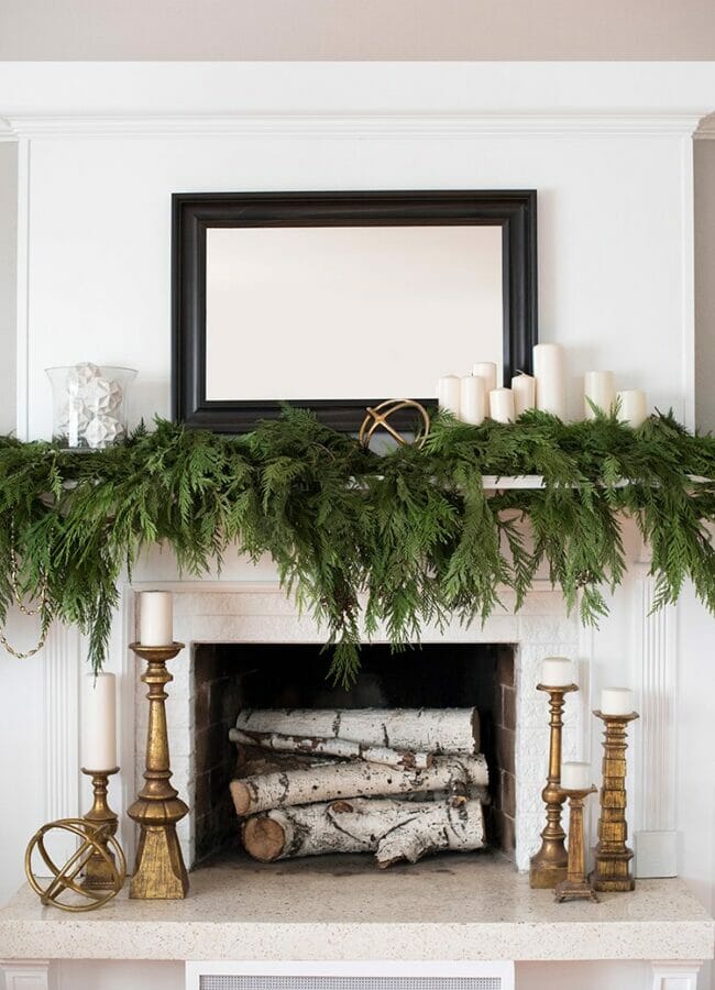 mantle with lots of greenery and white candles 