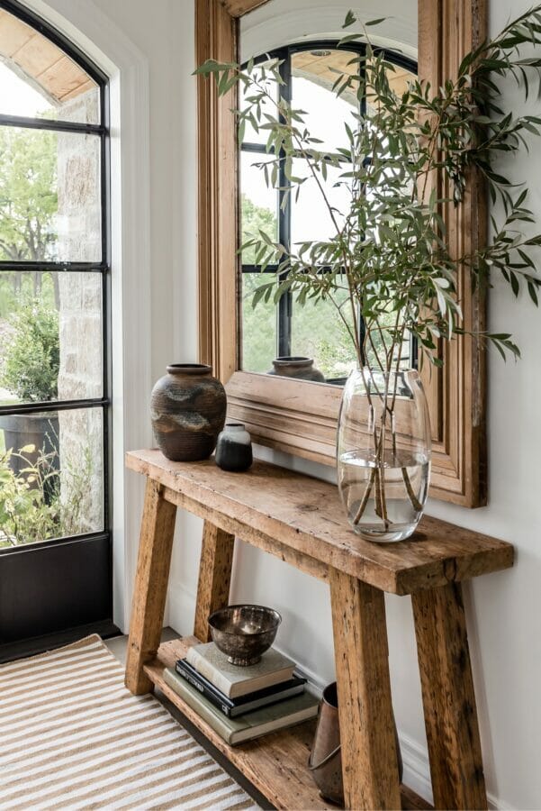 rustic table with large mirror and glass vase with branches