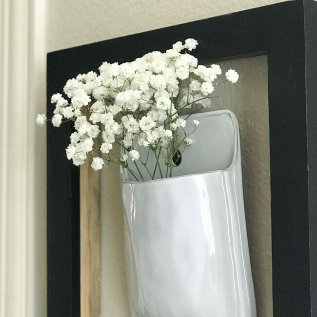 black frame with white wall pocket and Baby's Breath