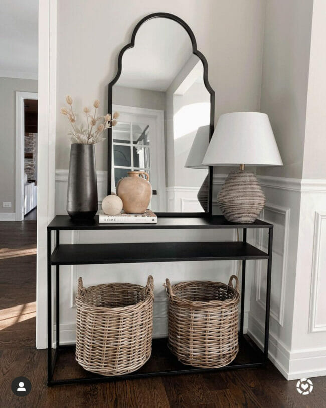 dark metal table with mirror, and two baskets on bottom