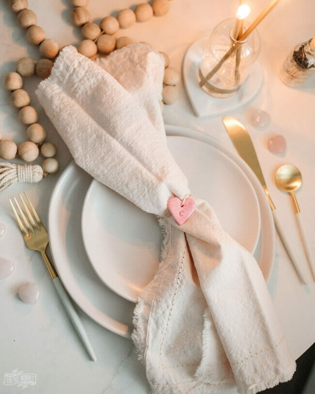 pink clay heart tied around a white napkin and place setting