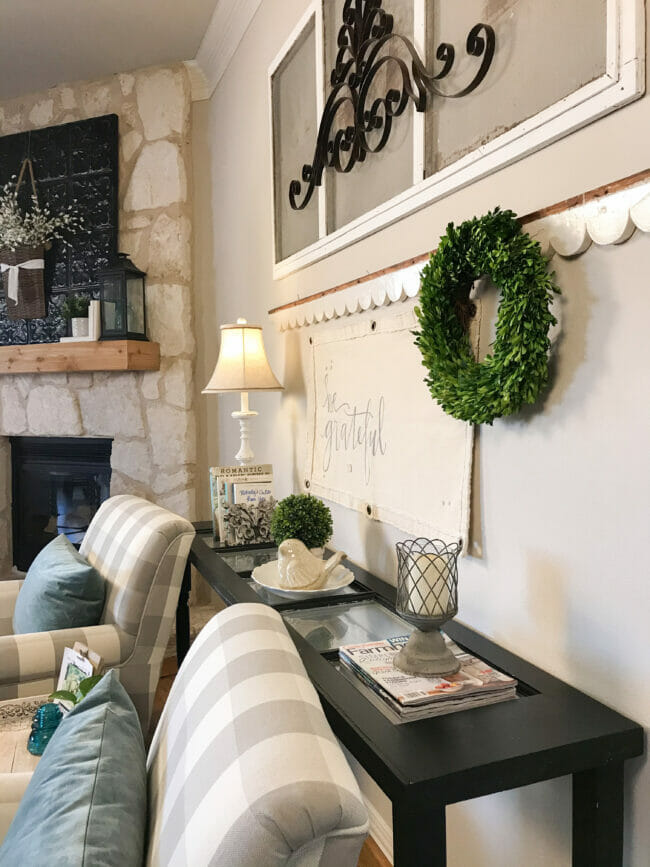 black console table decorated with spring wreath, bird and plants