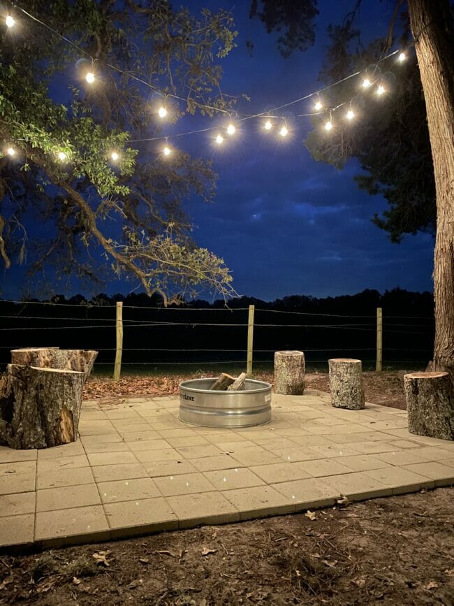 outdoor firepit area with string lights and log seats