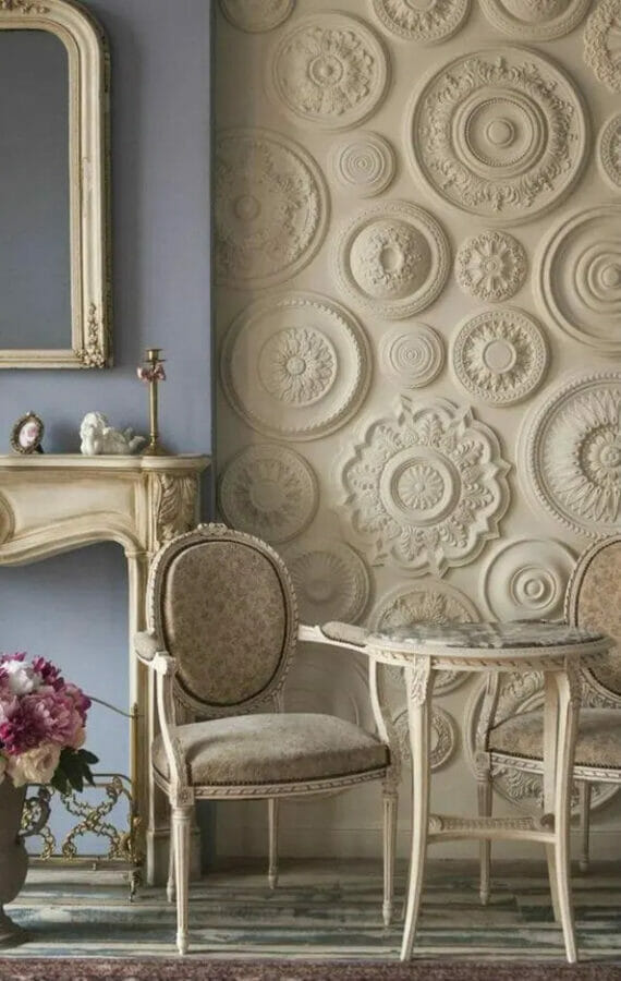 wall full of beige medallions with french country fireplace and table in front of it