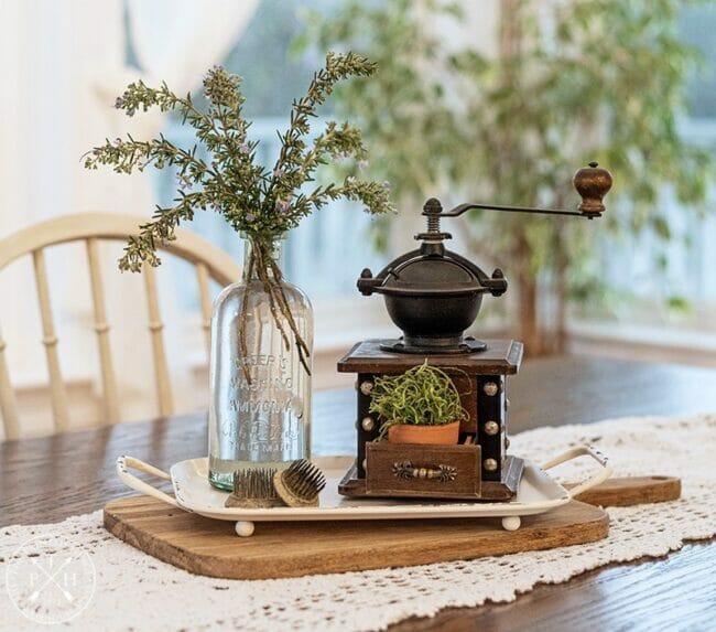 glass jar with stems and an antique grinder with potted plant as a table centerpiece