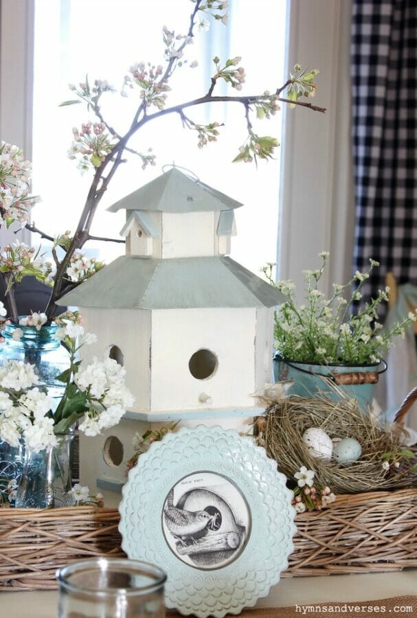 white birdhouse with spring stems, blue jars and bird nest