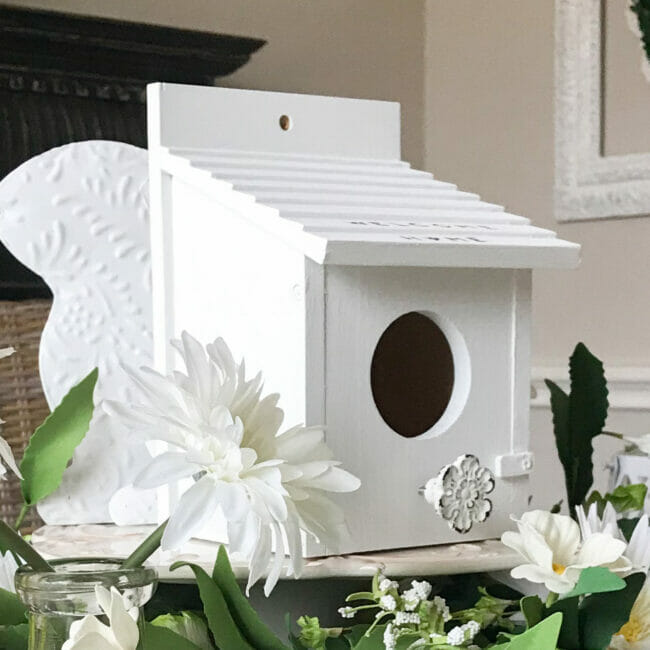 white birdhouse with greens and white daisies