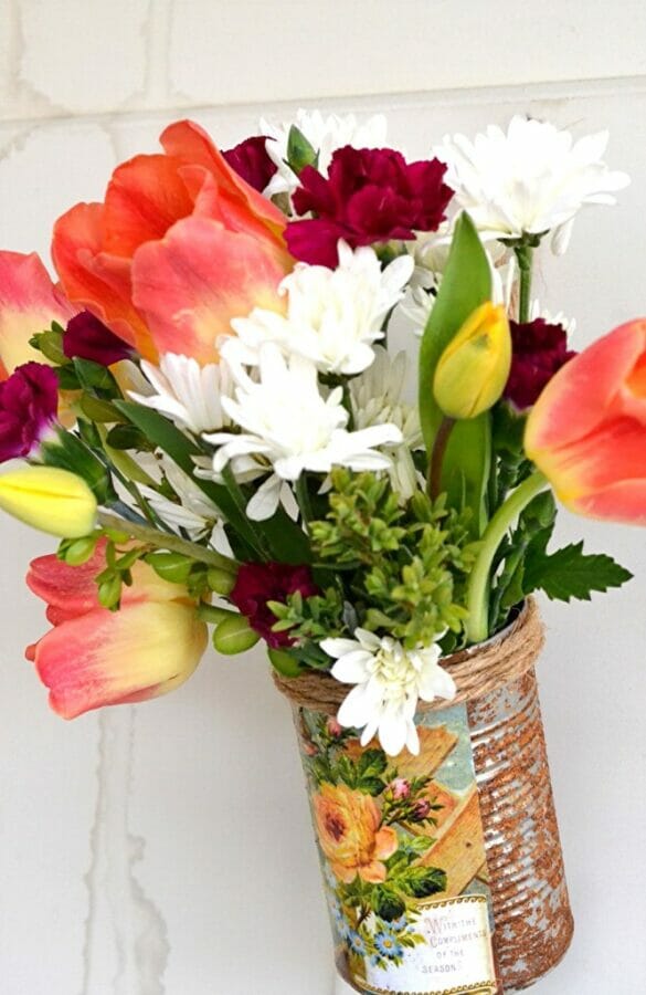 flowers in a rusty can hanging on door