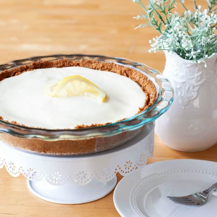 lemon pie on cake stand with white pitcher with flowers