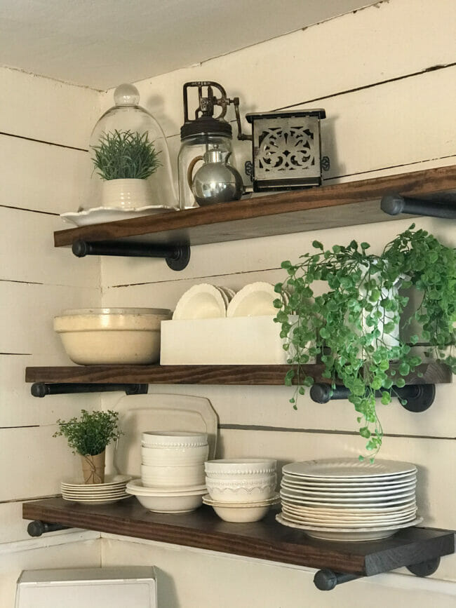 open kitchen shelving with white dishes and plants