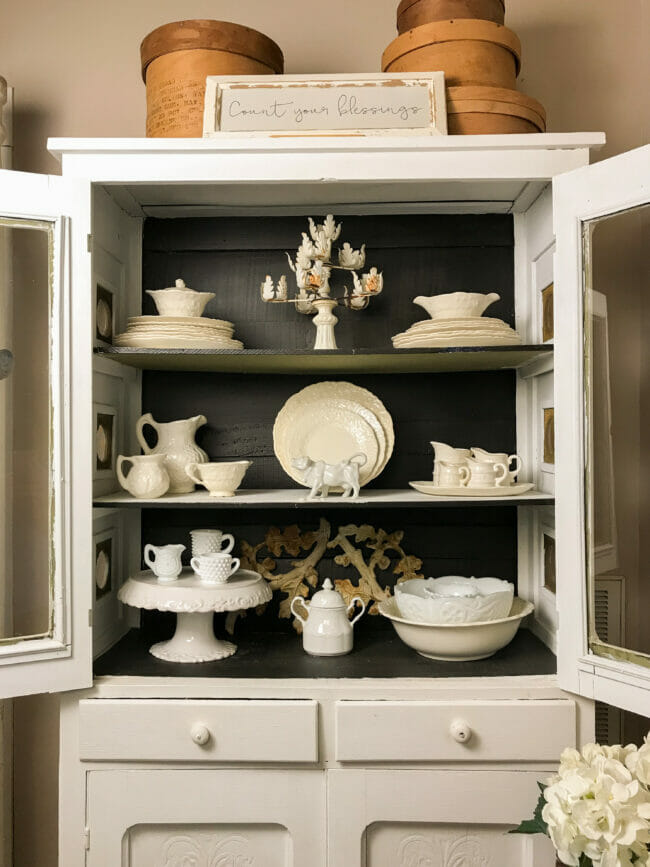 white dining hutch with black background and white dishes