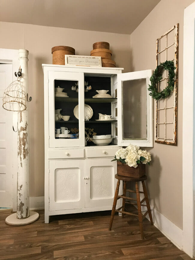 white hutch with column, stool and white dishes