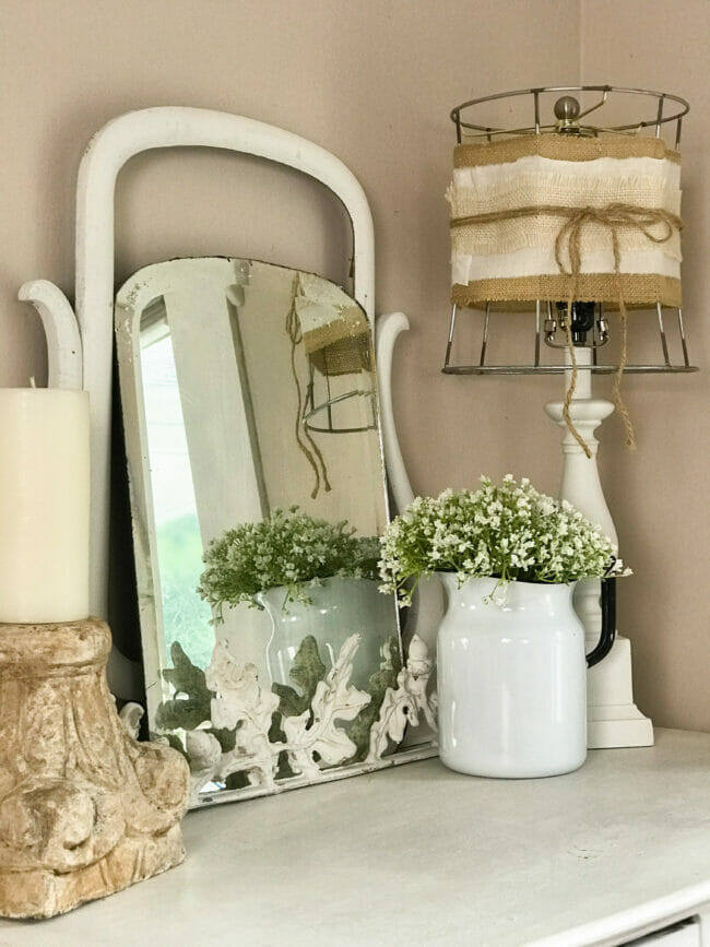 antique mirror, candle and lamp on top of a dresser