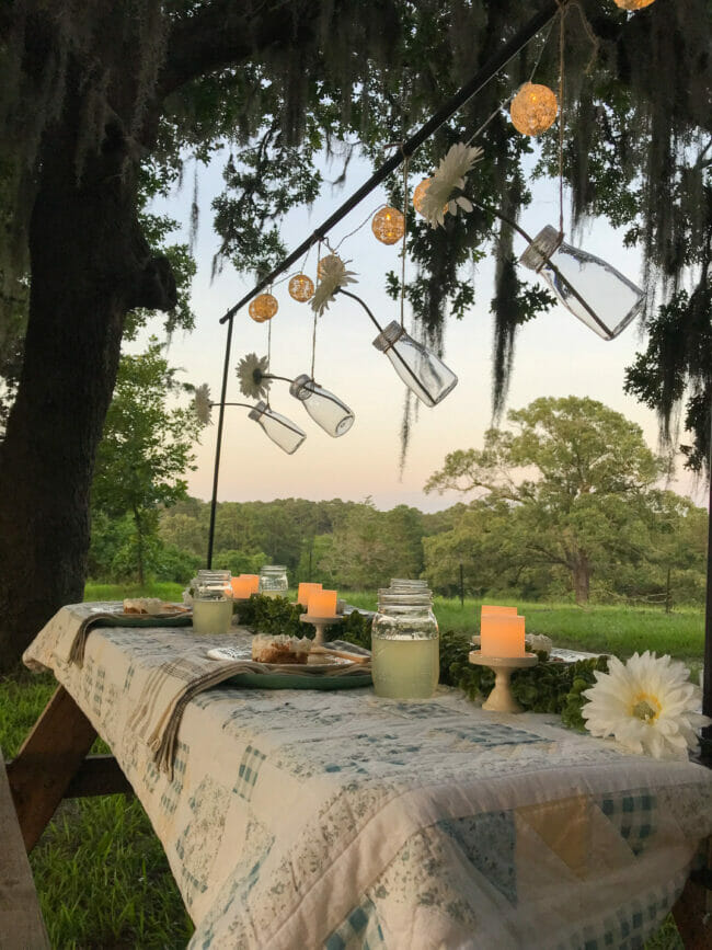 outdoor Picnic table with quilt and hanging bottles with flowers
