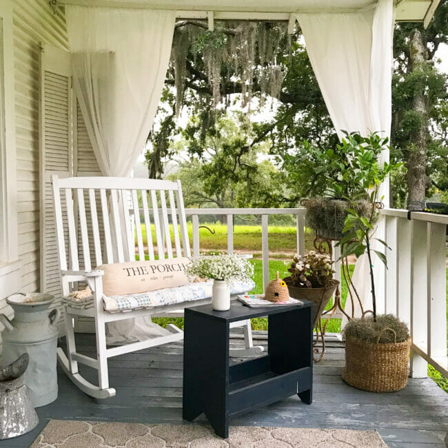 porch with plants, white rocking bench and navy stool