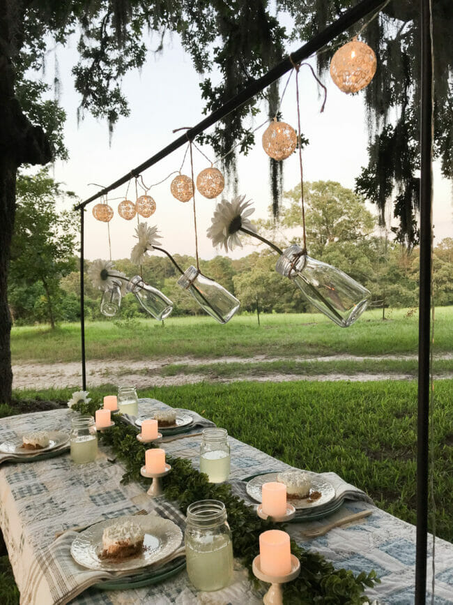 outdoor table with rod and hanging bottles with flowers