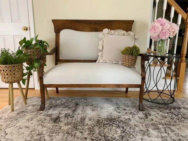 antique settee with rug, table and flowers