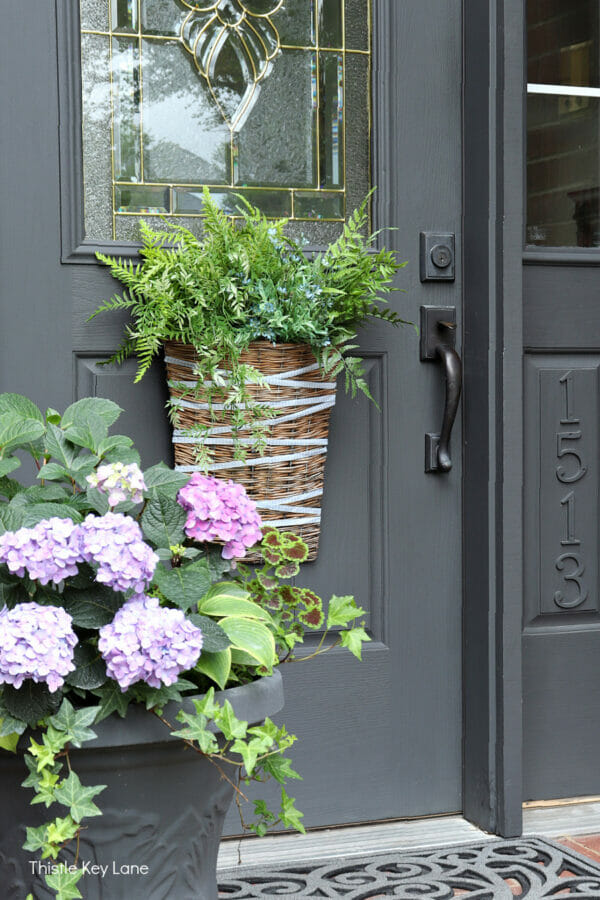 gray front door with basket and greenery