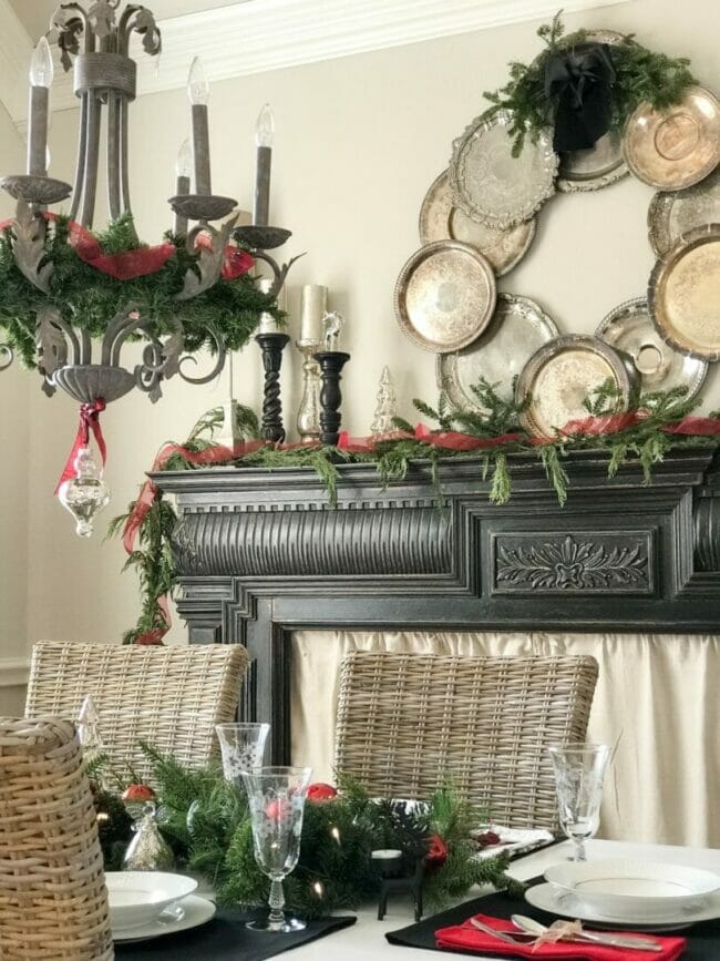 black mantel with silver tray wreath and chandelier with greenery