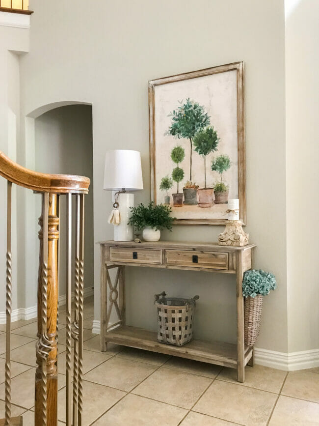 console table with lamp, topiary painting and accessories