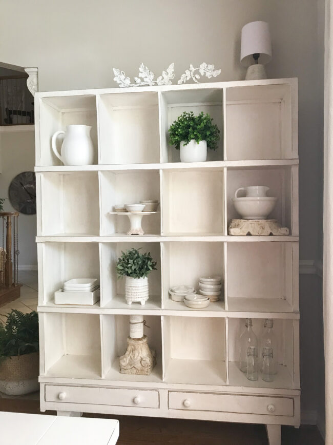 full cubby shelf with pottery and faux plants