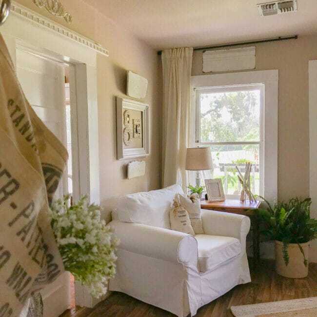 white chair, window with plants and architectural salvage pieces on walls