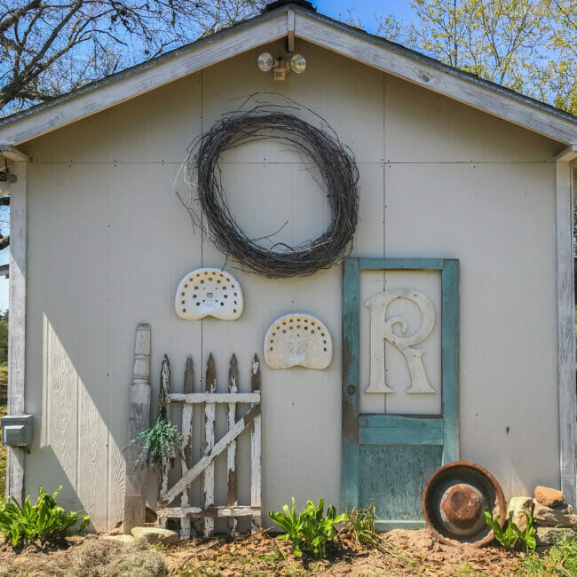 side of barn with blue door, wreath and fence panel