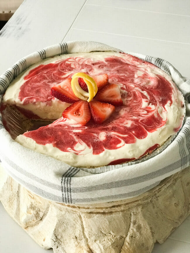 strawberry lemonade pie with slice out and towel wrapped around it