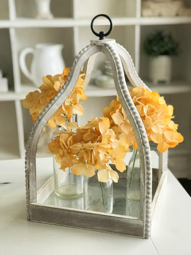 white beaded lantern with 3 glass bottles and gold hydrangeas