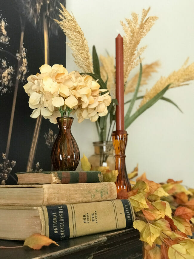 small amber vase sitting on books with hydrangeas