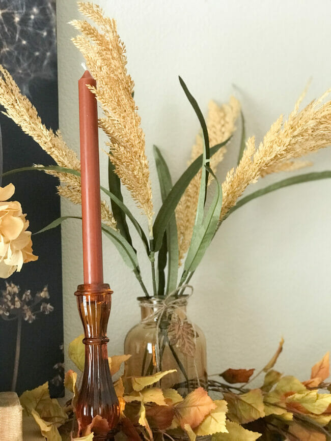 amber glass bottle with leafy stems and candlestick