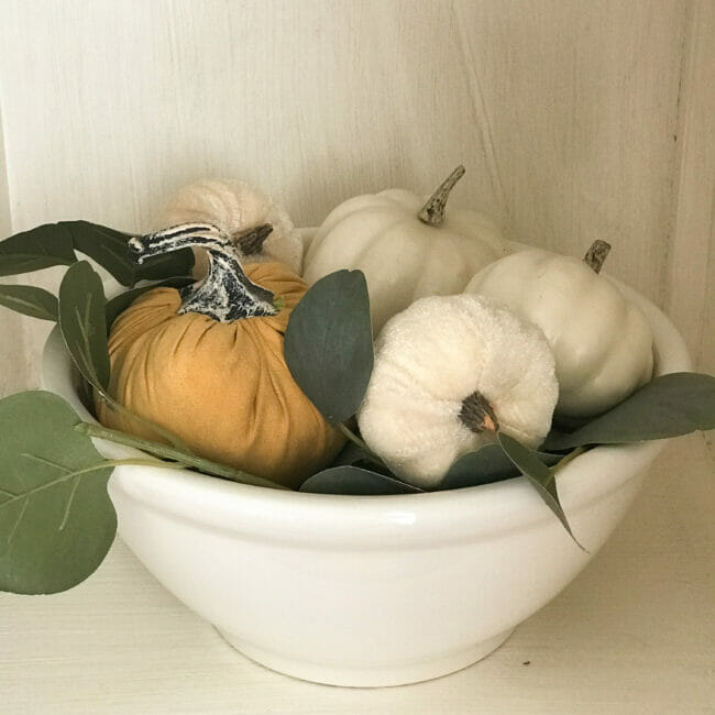 white bowl with white pumpkins and one gold pumpkin