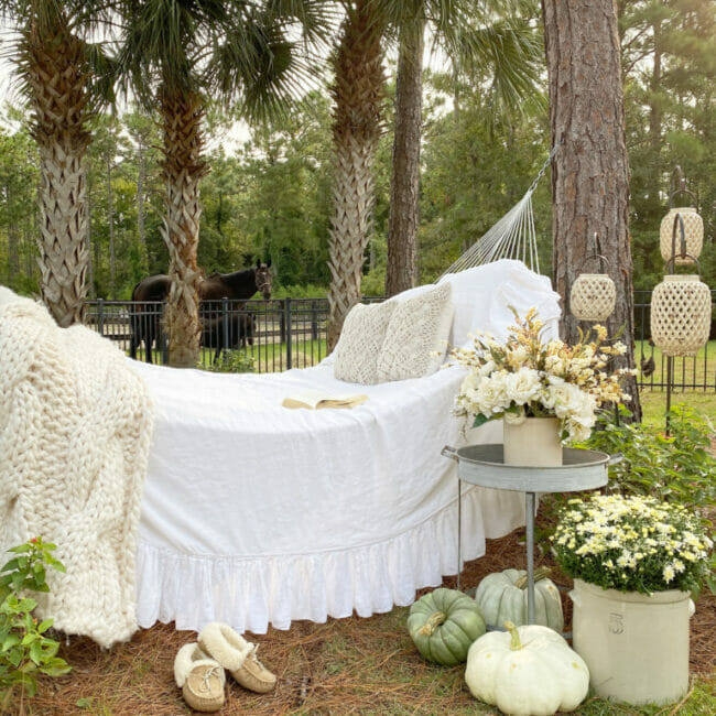 hammock with white bedding and pumpkins with horse in background