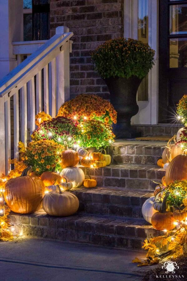 pumpkins and mums on bricked stairs with lights