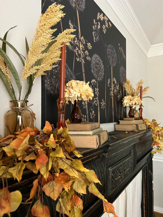 black mantel with fall leaves, candles and books