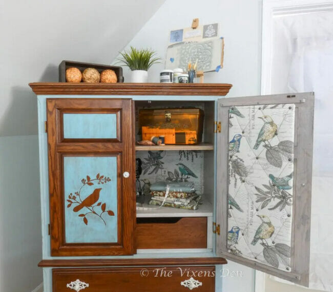 blue and stained cabinet with bird insert on door