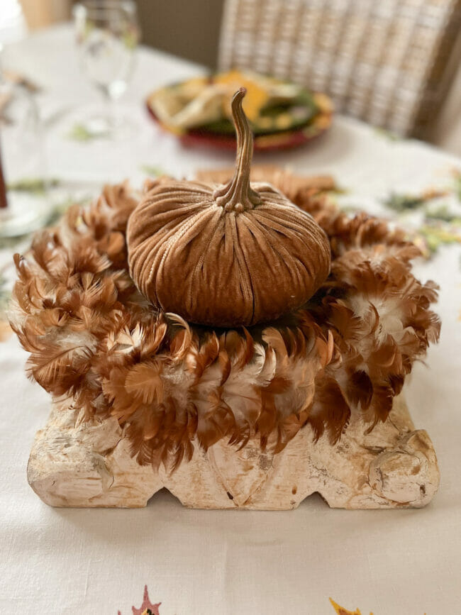 rust colored feather wreath and velvet pumpkin as centerpiece
