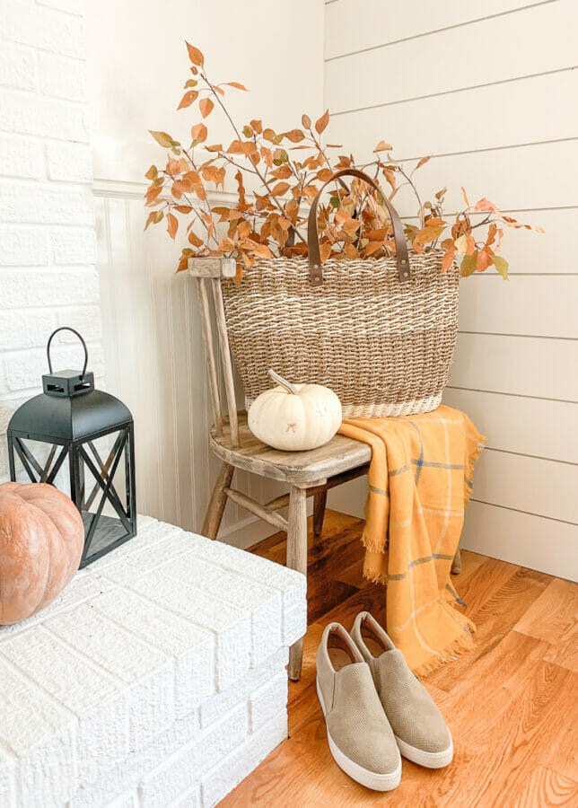 chair with basket of fall branches, lantern and shoes on floor