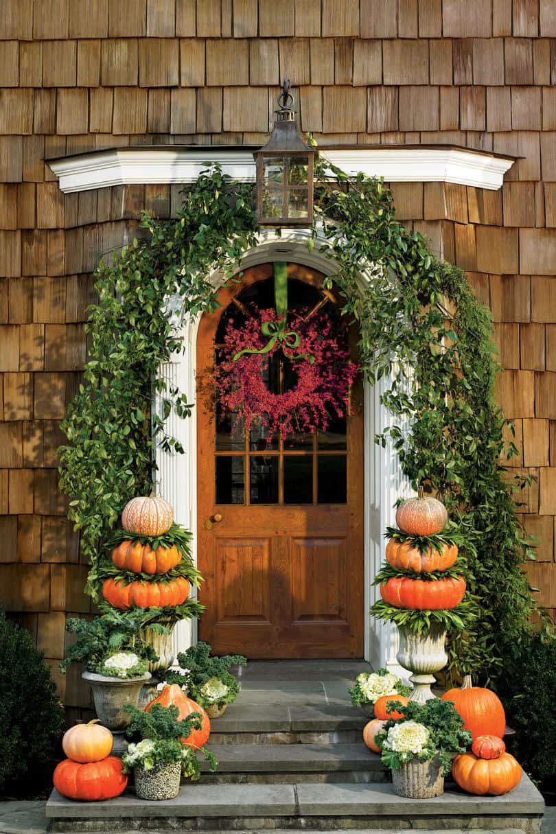 shingled house with arched door and pumpkin topiaries