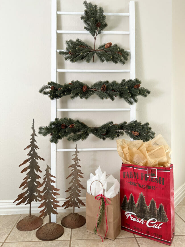 white ladder with green stems creating a tree shape with gifts