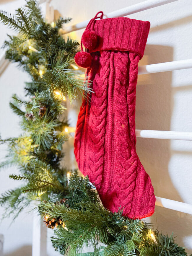 red sweater stocking hanging on a white ladder with lit garland