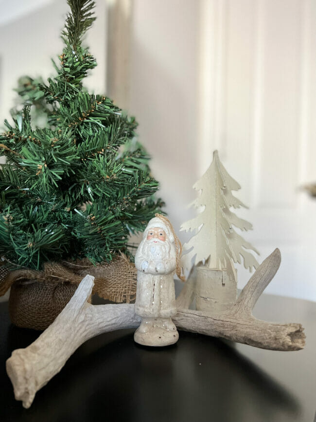 small white Santa with white wooden tree, antler and a taller green tree